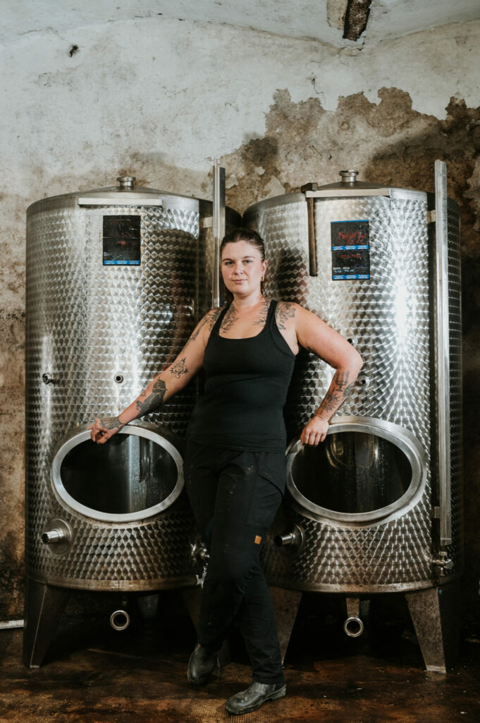 Person vor zwei großen metallischen Flüssigkeitslagertanks in einem fleckigen Raum.